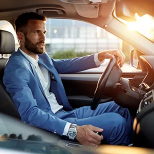 Photographie d'un homme en costume au volant d'une voiture